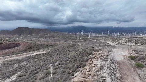 Drone Flies Over Rugged Terrain Toward Wind Turbines at Horizon Stock Footage 310064589