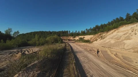 A drone flies over a sandy quarry with surrounding forest, capturing the rugged Vidéo 283947412
