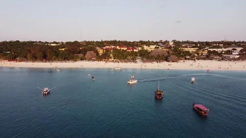 The drone flies over the sea in which boats float. A beach with houses and palm  Stock Footage 194554731