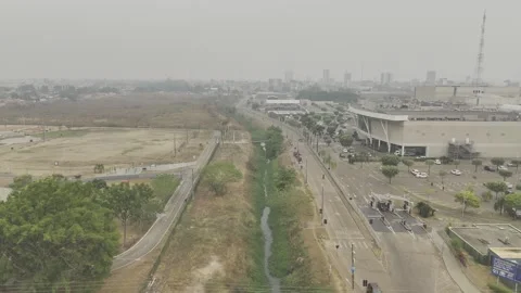 Drone flies over small canal toward smoke-covered skyline from wildfires Stock Footage 285106307