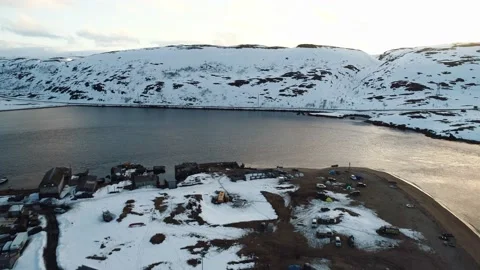 The drone flies over a small northern village on the coast surrounded by snow Stock Footage 169464779