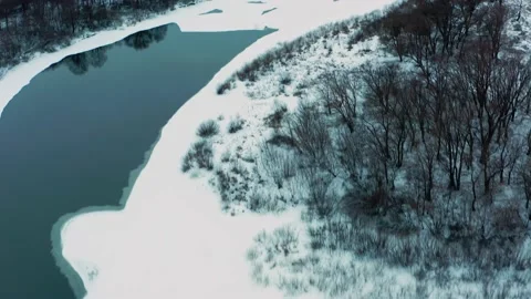 Drone flies over the snowy flat landscape with a frozen river. Aerial view of Stock Footage 169667455