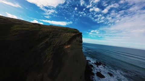 Drone flies over steep cliff edge overlooking vast ocean horizon Stock Footage 340905293
