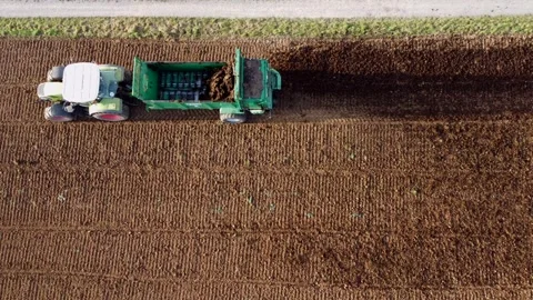 Drone flies over tractor with manure spreader in action on field, aerial view Stock Footage 253500482
