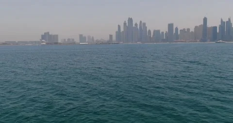 The drone flies over the waves of the sea towards the city on the shore. Dubai Stock Footage 249321657