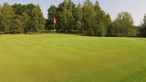 A drone flies over well with flag above green golf course Stock Footage 79840789