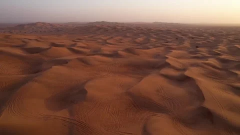 A drone flies over a white SUV driving through the sand dunes of the desert Stock Footage 246896561