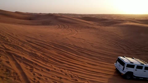 A drone flies over a white SUV driving through the sand dunes of the desert Vídeo Stock 247622113