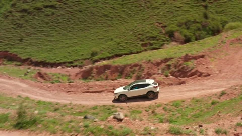 A drone flies over a white SUV traveling through the mountains of Kyrgyzstan Video stock 276645665