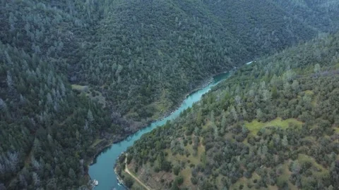 Drone flies over winding river in densely forested valley Stock Footage 303696872