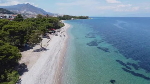 A drone flies parallel to the beach above the small town of Xylokastro in Stock-Footage 261486053