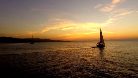 Drone flies past small sailboat in harbour at Sunset Stock Footage