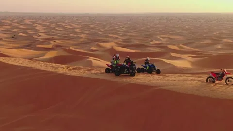 The drone flies to the quadra in cycles standing on sand dunes in the desert of Stock Footage 247428987