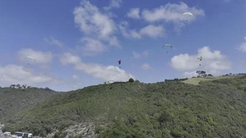 Drone flies to the right below a sky full of paragliders on a sunny day Stock Footage 326765904