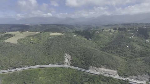 Drone flies to the right high over paragliders on a sunny day on Garden Route Stock Footage 326769734