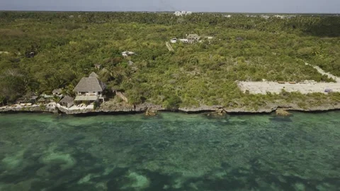 Drone flies to right over clear blue waters while facing forested coastline Stock-Footage 346481605