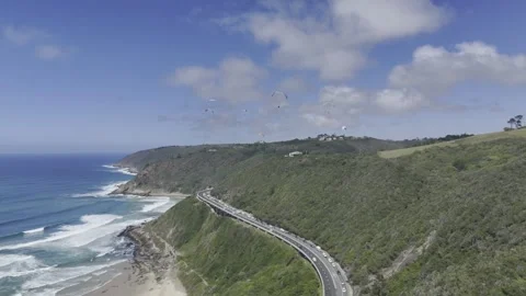 Drone flies to the right over coastal highway with paragliders in the air Stock Footage 326702435