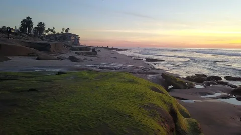 Drone flies sideways above tidepools to beach to open ocean towards sunset Stock Footage 102212950