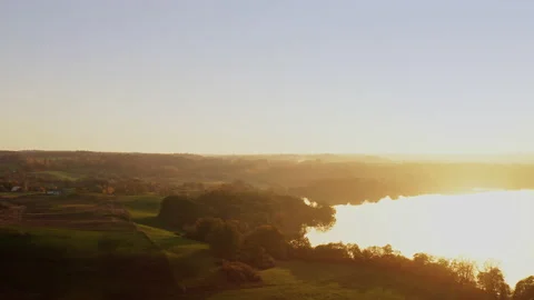A drone flies sideways, on one side of the picture are green fields, trees and Stock Footage 239101264