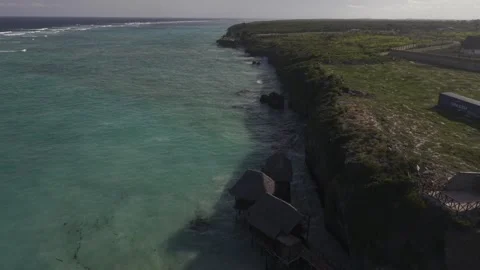 Drone flies south over Usumba Rock restaurant and along beach at high tide Stock Footage 344112447