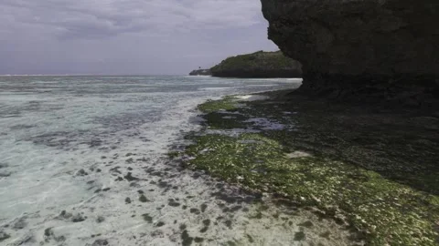 Drone flies southwest low over tide pools next to cliffs on a sunny morning Stock Footage 344092899