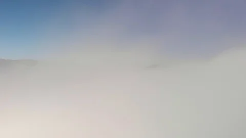 Drone flies though clouds to reveal mountain peak in the distance Stock Footage 128274943