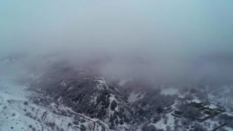 The drone flies through the clouds over the snow-covered mountains. Cloudy Stock Footage 311792913