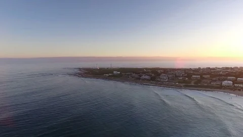Drone flies towards Cape Saint Francis lighthouse during golden sunset 스톡 동영상 85140350
