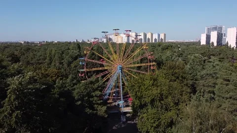 A drone flies towards a spinning multicolored metallic Ferris wheel Stock Footage 145058299