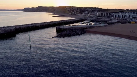 Drone flies towards sunset over the harbor of West Bay Stock Footage 94366533