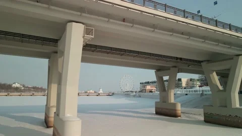 A drone flies under a road bridge in winter towards the Ferris wheel. Stock Footage 195953223