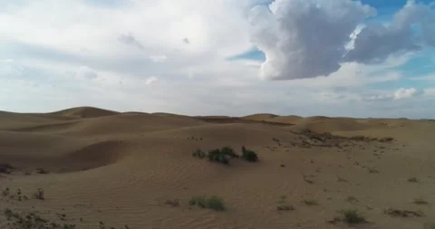 Drone flies very low over the desert sand dunes, kicking up dust with its Stock Footage 253861558