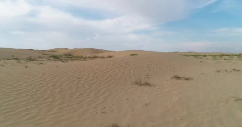 Drone flies very low over the desert sand dunes, kicking up dust with its Stock Footage 255309512
