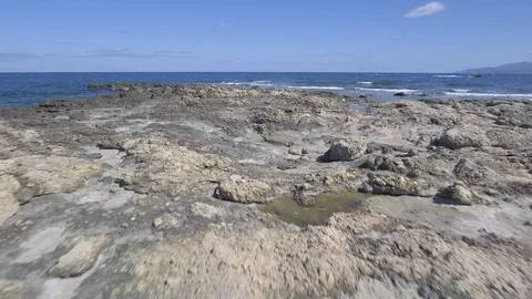 A drone flies very low towards the sea while the rocks breaks the waves Stock Footage 100819153