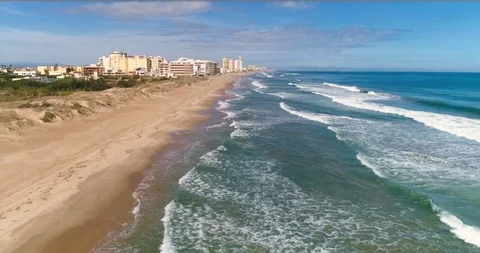 Drone flies wide beach next to coastal city from a bird's eye view Stock Footage 124374546