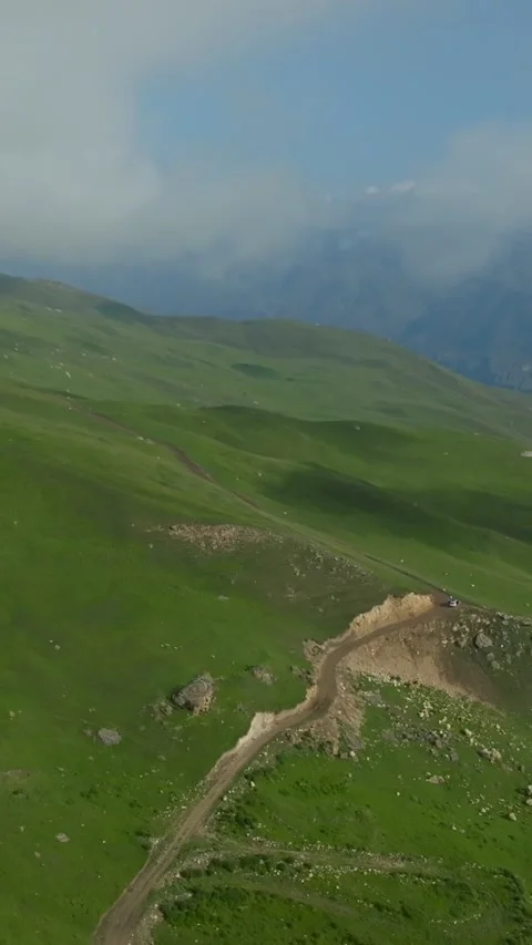 Drone flight above green Dagestan hills with winding dirt track in Caucasus Stock Footage 346557467