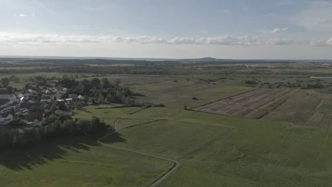 Drone flight above green field and small City Stock Footage 240437342