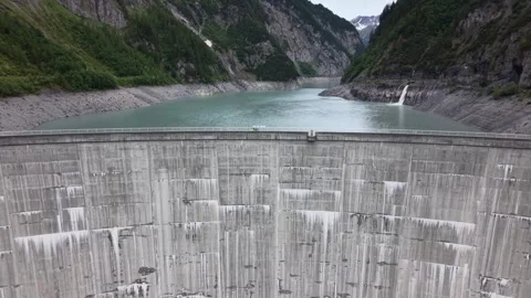 Drone Flight Across Alpine Dam Revealing Reservoir Between Mountain Peaks Video stock 336368231