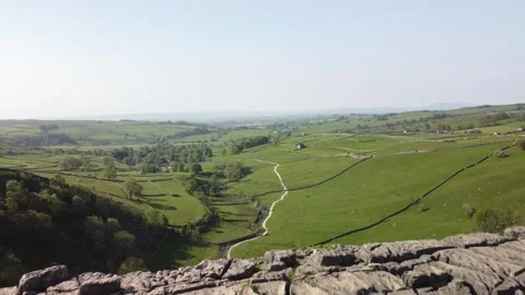 Drone Flight Across a Rocky Cliff in a Lush Green Valley with Path Stock Footage 242798545