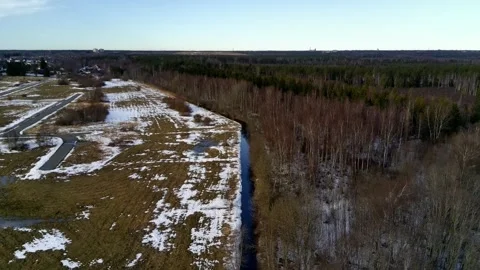 Drone flight along stream between forest and fields in winter Stock Footage 331070392