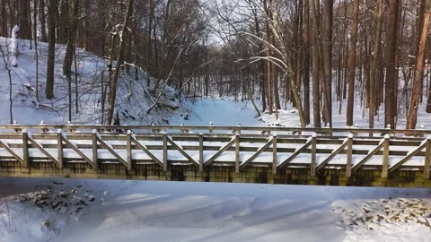 Drone flight along the sun's rays over a frozen river over a snowy bridge, 4K Video stock 328268437