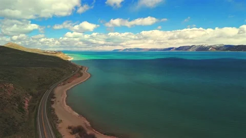 Drone flight along winding Bear Lake Utah shoreline road with turquoise water Stock Footage 335080671