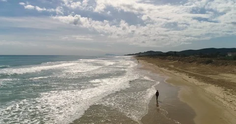 Drone flight and general view of woman walking on sea with big waves Stock Footage 124373273