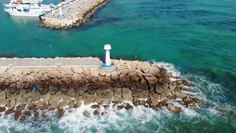 Drone flight around the lighthouse over the breakwater and the sea Stock Footage 161643367
