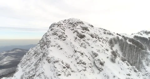 Drone flight back over a snowy mountain peak Stock Footage 85890891