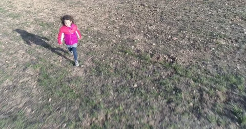 Drone flight back of a pretty little girl running through green meadow Stock Footage 88596346