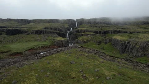 Drone flight into basalt canyon with tall waterfall in fog, Reydarfjordur Stock Footage 346552255