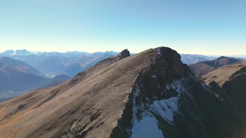 Drone flight beside snowy alpine ridge at sunset light Stock Footage 336022893