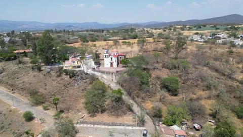 Drone flight from Cocula town towards hilltop La Cruz temple, dry landscape Stock Footage 318669508