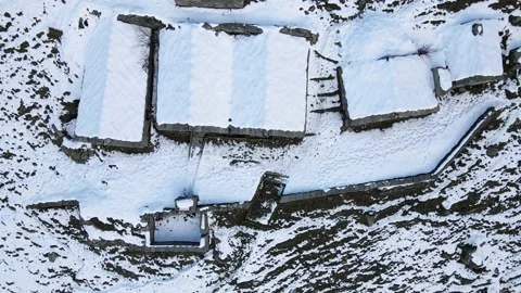 Drone flight in mountain with snow over old constructions (alpine pasture). 4K Stock Footage 148031477